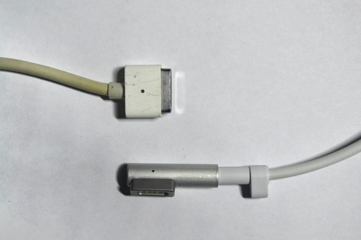 The original T-shaped MagSafe connector above the later L-shaped MagSafe connector