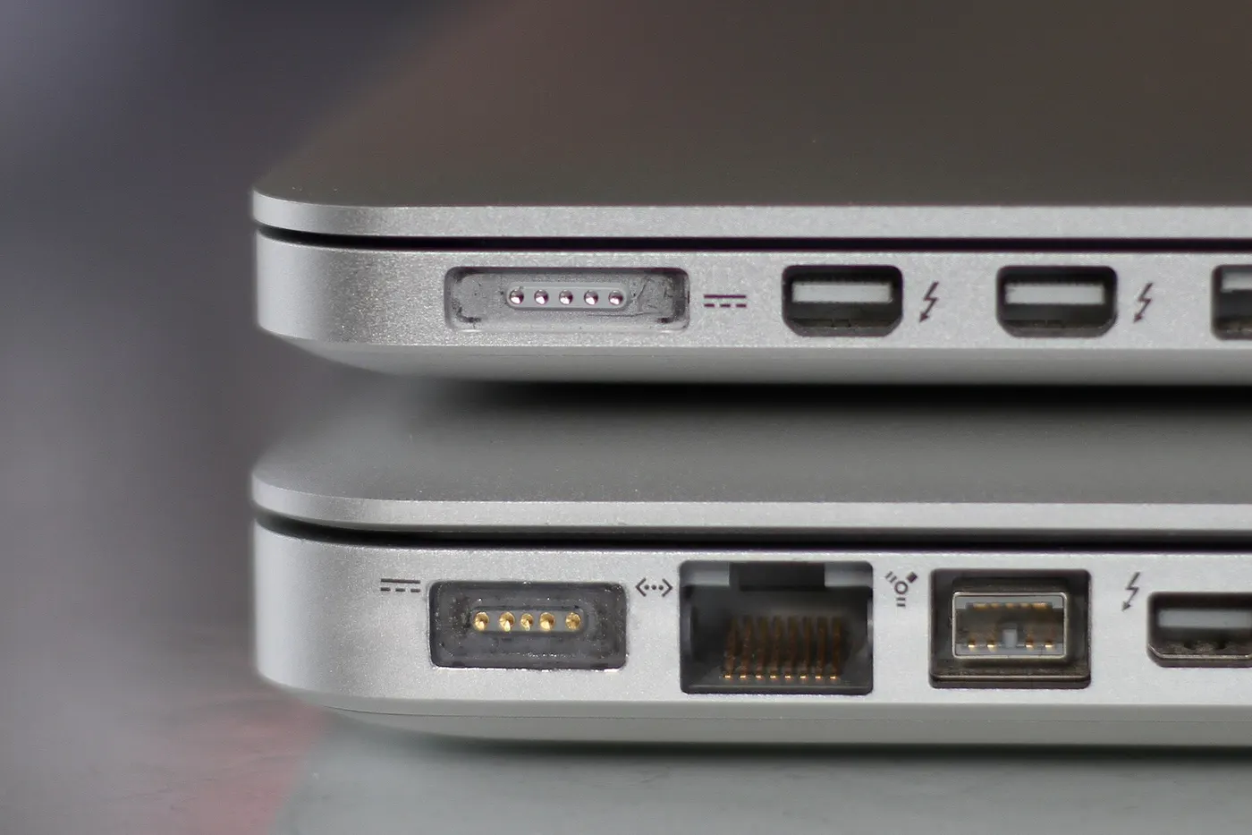 The side of two MacBook Pro laptops: the wider, thinner MagSafe 2 port on top and the original MagSafe port below